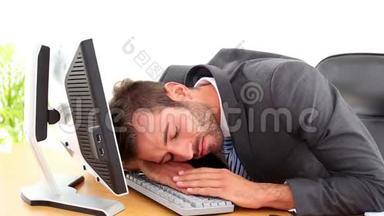 精疲力竭的商人睡在他的办公桌前