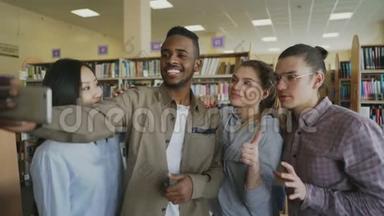 一群国际学生在大学图书馆的智能手机摄像头上开心地微笑和自拍