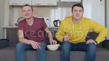 两个男人正在吃爆米花，看<strong>足球赛</strong>