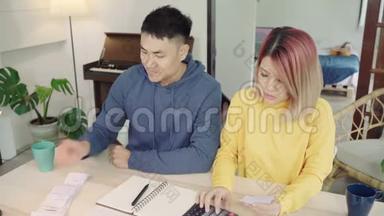 年轻时强调，亚洲夫妇管理财务，在现代家庭使用笔记本电脑和计算器审查他们的银行账户。