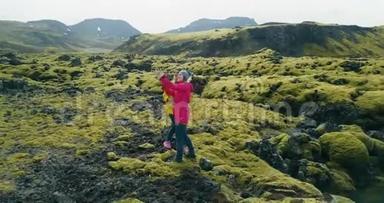 冰岛熔岩场上两名妇女的鸟瞰图。 直升机<strong>飞</strong>来飞去</strong>的游客在智能手机上自拍照片。