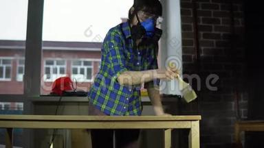 女木匠在车间用刷子从桌面上敲打木屑。