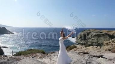 一位快乐的新娘站在海边，戴着一层在风中飘扬的婚纱。 幸福婚姻的概念