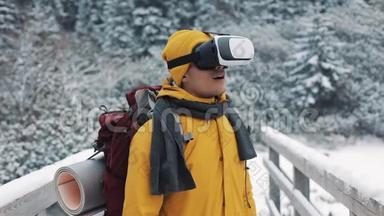 穿着黄色外套、享受虚拟现实眼镜耳机或在冬季山区户外玩3D<strong>游戏的</strong>年轻魅力男子