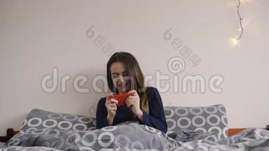 女人在床上开心地玩手机游戏