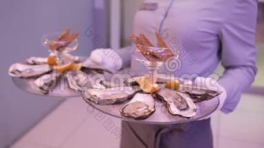 服务员端着牡蛎放在透明的圆形托盘上，牡蛎放在冰面上，柠檬片放在中间