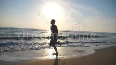 日出时，年轻运动男子沿着海岸快速奔跑的剪影。 赤脚在海滩上训练运动男孩
