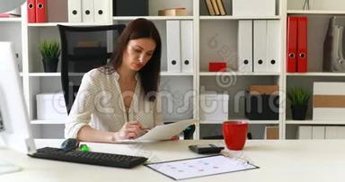 女商人坐在办公室椅子上看文件。
