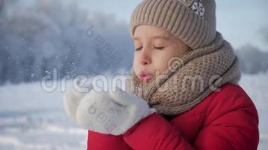快乐的年轻女孩玩得开心，在美丽的冬日享受新鲜的雪。 戴着温暖手套的女孩吹雪。 户外活动