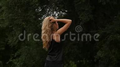 自然背景下金发女人的背景。 美丽的女孩摆着飞舞的头发。 慢动作