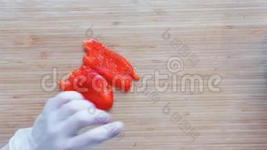 一个厨师把一个红椒切在一个木切割板上。 上景。