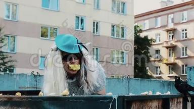 <strong>男</strong>人戴着女人的<strong>假发</strong>戴着太阳镜，蓝帽子戴在垃圾箱里，嘴里放着苹果。 仿造