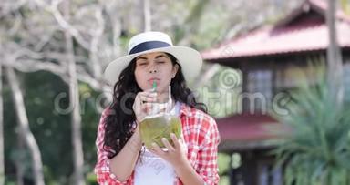 美丽的女孩喝椰子鸡尾酒，棕榈树上快乐的微笑青年妇女旅游