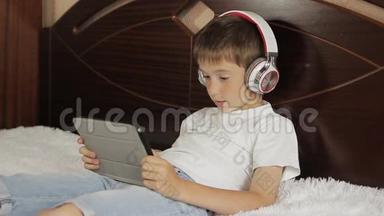 这个男孩躺在床上听音乐，或者用他的平板电脑上一节电子学习课，它连接着一对