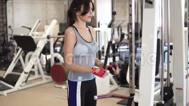 运动员在健身房的机器上做<strong>三头肌</strong>的练习。 穿运动服的女孩训练