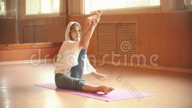 年轻女子坐在瑜伽垫上做腿部伸展运动舞蹈工作室