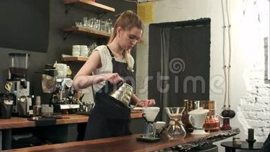 年轻的女咖啡师在时髦的现代咖啡馆咖啡店里把开水倒在咖啡场上，倒在地上