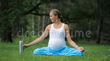 怀孕瑜伽在莲花的位置与热水瓶<strong>喝茶</strong>。 在公园的草地上，户外，健康的<strong>女人</strong>，<strong>女人</strong>。