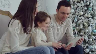 <strong>爸爸妈妈</strong>和他们的小儿子坐在沙发上用数码平板电脑