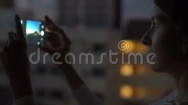 夜间在酒吧屋顶露台用智能手机拍摄城市景观的特写镜头