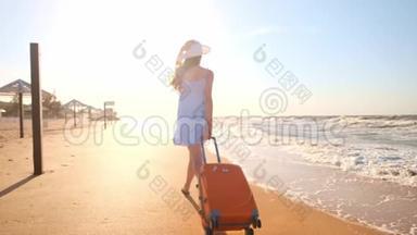 一个年轻的女人带着一个手提箱坐在海滩上。 一个年轻的女孩带着一个轮式手提箱沿着海滩散步。 一路走来