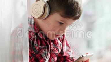 戴着智能手机耳机的男孩，穿着衬衫看动画片的小孩