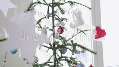 纸星星挂在窗户旁边的一棵圣诞树的前景上。 圣诞节的概念。 慢动作