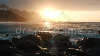 在加那利群岛的特内里费，海浪撞击岩石，在美丽的日落光线下喷射。