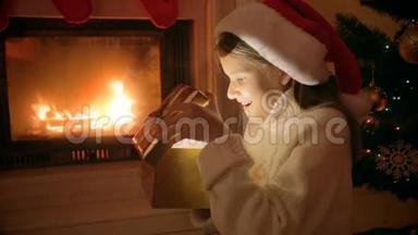 圣诞老人帽子里的幸福女孩的特写肖像，看着闪闪发光的圣诞礼品盒