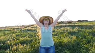 戴<strong>帽子</strong>的快乐年轻女子在夕阳下的绿野中享受<strong>夏日</strong>