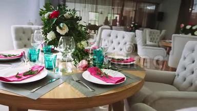 一张圆形的木制桌子，上面装饰着由白色盘子和粉色餐巾纸做成的花饰