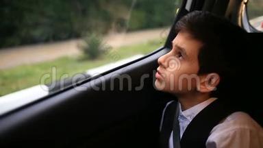 少年坐在车里看着<strong>窗外</strong>。 <strong>窗外</strong>闪烁着城市<strong>的</strong>树木和房屋