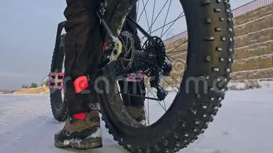 专业的极限运动员自行车站在户外一辆胖自行车。 骑自行车者在冬天的雪林中退缩。 男人走路