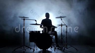 鼓手在鼓上大力演奏旋律。 黑色背景。 剪影