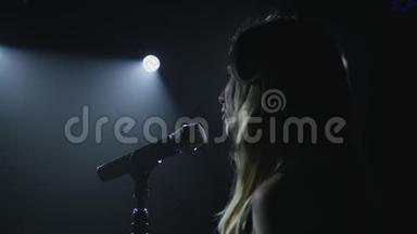 在黑色的烟雾背景上用麦克风特写歌手的脸。 歌手在舞台上唱一首歌