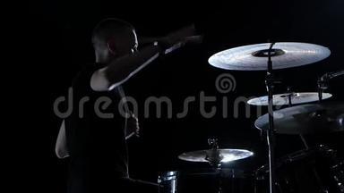 音乐家用棍子在鼓上演奏专业的好音乐。 黑色背景。 剪影。 慢动作