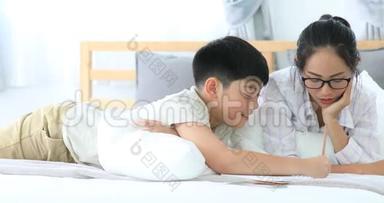 快乐的亚洲兄妹在床上休息，微笑着写字。