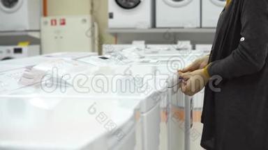 一位年轻女子在<strong>家</strong>电</strong>店里挑选洗衣机