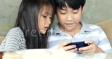 快乐亚洲家庭姐妹和兄弟在床上玩手机。