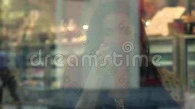美丽的黑发女孩在小咖啡馆喝热巧克力。 从外面透过窗户观看。 4K视频