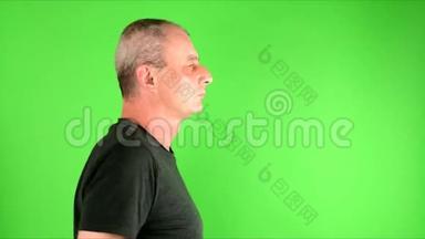 成熟的中年男人走路。 一个成熟的白人的肖像出现在绿屏前。 侧视。