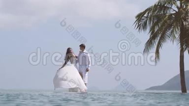 新娘正在玩她的白色婚纱。 年轻漂亮的男人和女人在海滩上互相拥抱。 快乐