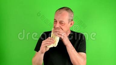 成熟的中年男人。 一个成熟的男人在绿色屏幕前吃快餐烤肉串的肖像，也叫陀螺。