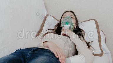 使用雾化器和吸入器进行治疗。 躺在沙发上的年轻女人通过吸入面罩吸入。 前景。