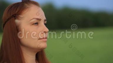 晚上，一个红发的年轻美女站在一片绿麦子的田野里，把麦穗放在她的地里