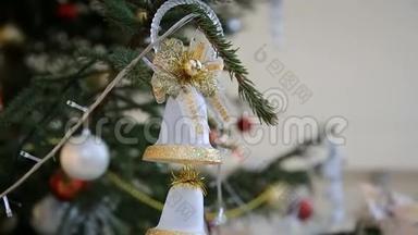 圣诞树上挂着<strong>金色</strong>的<strong>铃铛</strong>，挂在闪烁的彩色花环和特写中