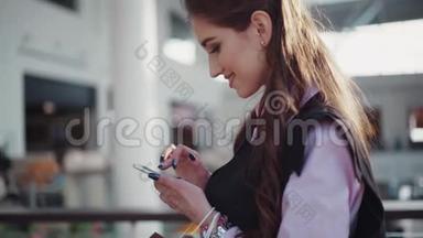 年轻的微笑的女人，穿着粉红色的衬衫和黑色的无袖夹克，打扮得漂亮，在购物中心。 这就是
