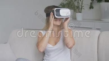 漂亮的年轻女子坐在客厅的沙发上，使用VR耳机。 4K拍摄的录像