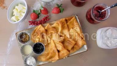 俄罗斯传统煎饼，布里尼提供果酱，酸奶油和草莓盘。 特写俯视图..