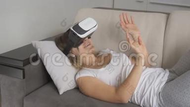 年轻微笑的女人躺在床上，用VR耳机观看360度视频。 4K分辨率拍摄的录像